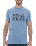 This design features a rustic font that reads "Real Men Smell Like Barbecue" Everyday lightweight smooth & comfy tee.  (Slim Fit). Available in Blue/Green/Grey/Brown