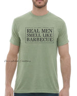 This design features a rustic font that reads "Real Men Smell Like Barbecue" Everyday lightweight smooth & comfy tee.  (Slim Fit). Available in Blue/Green/Grey/Brown